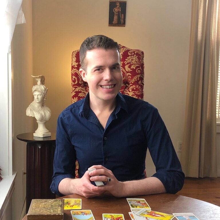Book a tarot reading with elliot oracle, sitting at a table with cards